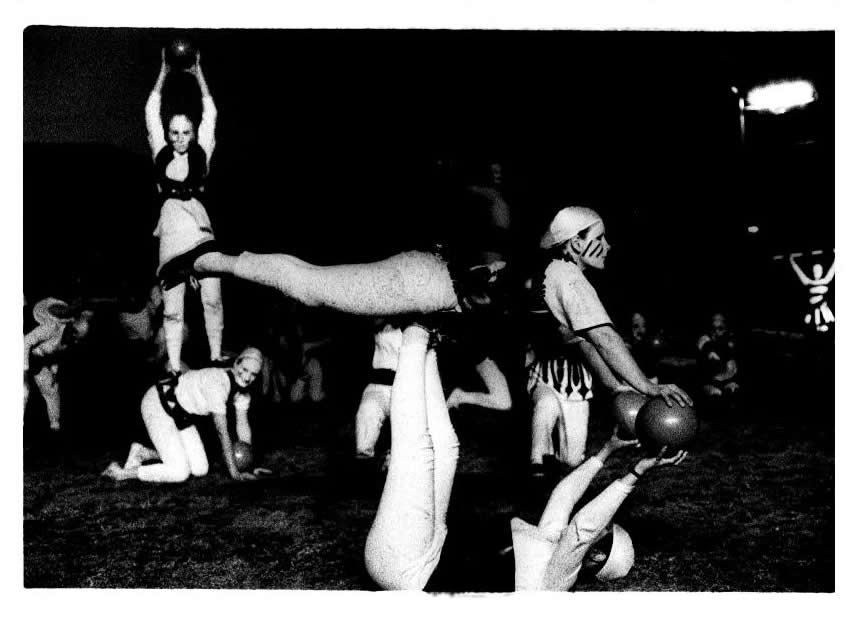A group of people performing circus tricks while in masks.