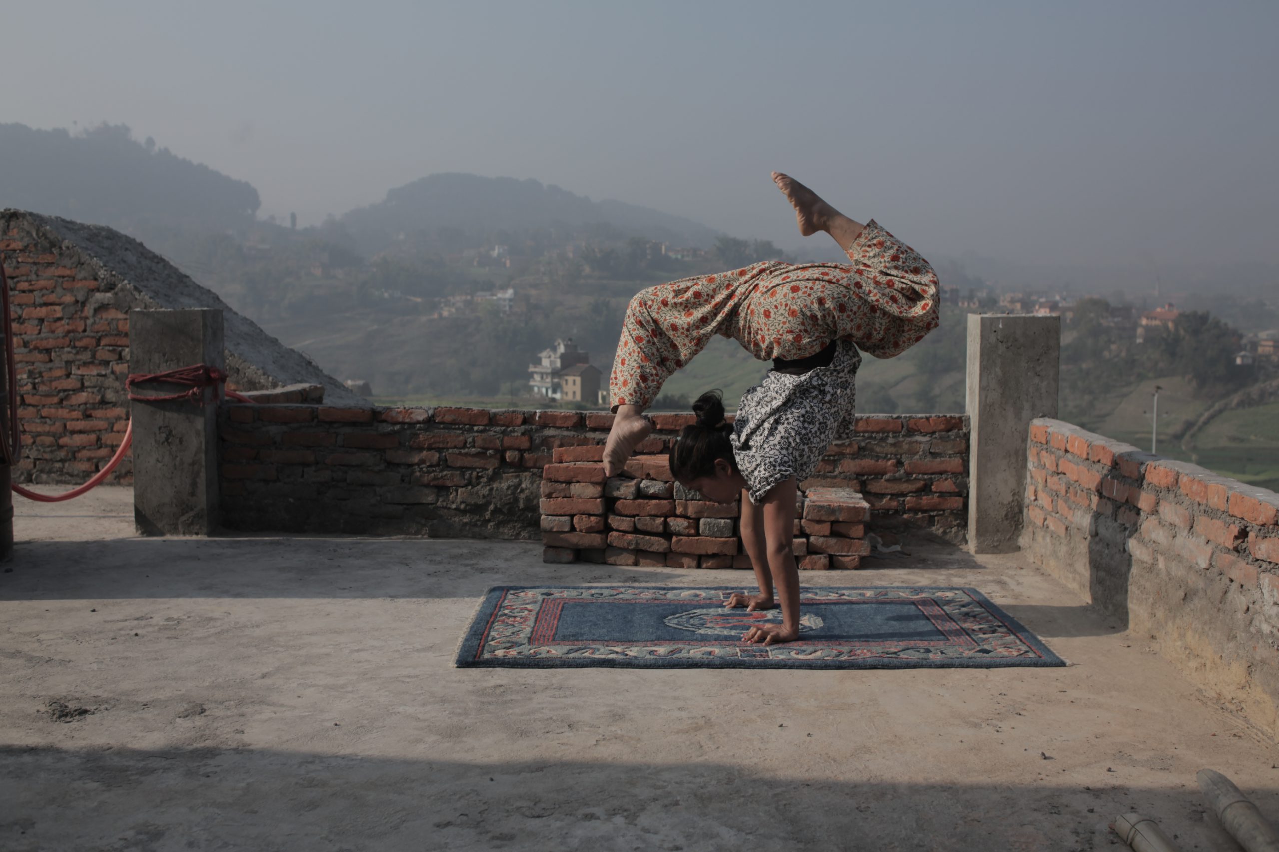 A woman doing a handstand atop a rooftop.