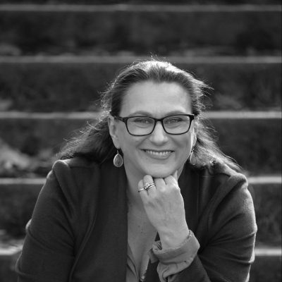 A smiling woman, wearing glasses.