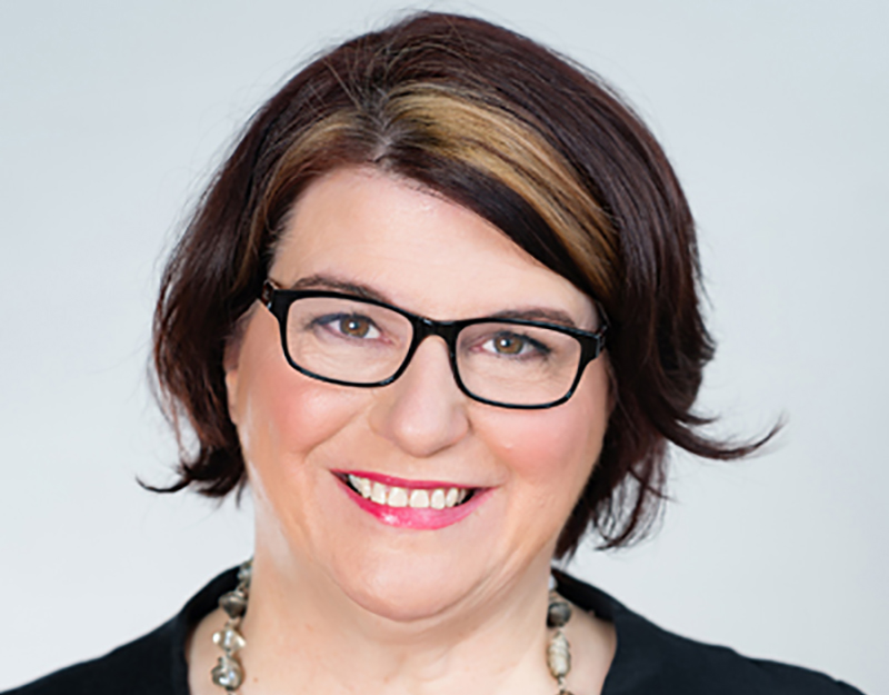A smiling woman, wearing glasses.