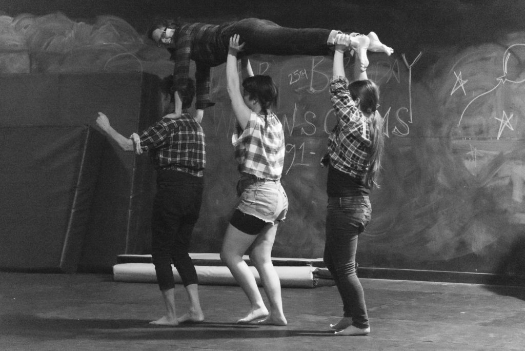 Three people holding one person above them.