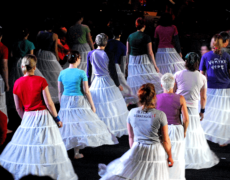 A group of people wearing white, hooped skirts.