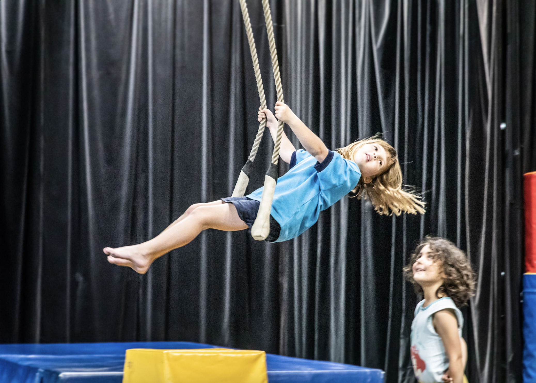 A child in Women's Circus training space swinging on a trapeze